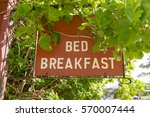 A Bed and Breakfast  hanging sign with vine leaves overhanging.