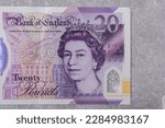 Small photo of Currency of Great Britain (England) pound. Banknotes with denomination and 20 images of Queen Elizabeth portrait on a gray background