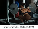 Small photo of Back view, woman lifting weight, squatting with barbell in gym, sporty woman exercising