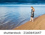 Small photo of Middle-Age brigand lass wearing leather equipment with sword is patroling along the seashore