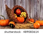 Harvest cornucopia with pumpkins, apples and gourds on rustic wood background