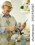 Small photo of Likeable aged man contacting someone online from his kitchen