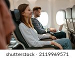 Cheerful woman sitting in passenger chair in airplane