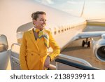 Joyful female stewardess standing near airplane at airport