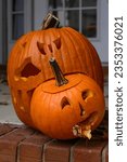 Small photo of Comical carved large Halloween pumpkin eating a smaller carved Halloween pumpkin