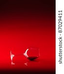 Small photo of single glass of red wine lain down on red background