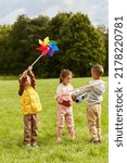 Small photo of childhood, leisure and people concept - happy kids with pinwheel having fun at park