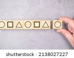 Small photo of Arrange the geometry shape on the wood cubes into same sequence pattern, standardized, logic, or basic IQ test concept