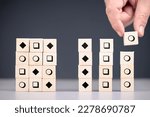 Small photo of Closeup hand rearrange the wood cubes with confused symbols on the left to the same category on the right