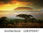 Mount Kilimanjaro and clouds line at sunset, view from savanna landscape in Amboseli, Kenya, Africa