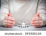 Airplane model surrounded by hands in gesture of protection. Concept of aircraft industry, airline safety, security and insurance.