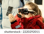 Small photo of Kid watching solar eclipse with glass dark filter and several sunglasses, funny little girl looking eclipse of sun. Child viewing eclipse in sky. Concept of people, weather, science and space.