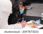 Small photo of New York, NY - December 28, 2021: A woman writes a message to burn it in the incinerator set in Latin America tradition in the middle of Times Square during Good Riddance Day
