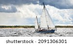 Small photo of Old expensive vintage wooden sailboat (yawl) close-up, sailing under dramatic sky before the thunderstorm. Sailing yacht regatta. Epic cloudscape. Kiel, North Germany