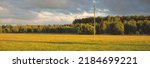Small photo of Green field and forest after the rain. Transformer pole close-up. Dramatic sunset sky, epic cloudscape. Fickle weather. Latvia. Cyclone, storm, meteorology, ecology, climate change, natural phenomenon