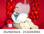 Funny happy bearded retro style man in the blue vest holding big teddy bear for Valentine day