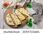 Small photo of Hearty tarte flambee from Alsace with onions, smoked bacon and munster cheese hot from the oven, served with Alsatian white wine
