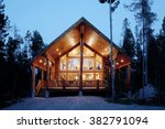 Exterior view of a modern log cabin at night.