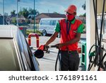 African attendant at a gas station handling a pipe nozzle refueling a car