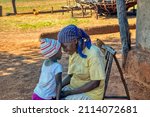 Small photo of Granny telling a story to her granddaughter in the yard of a village in africa