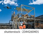 drone operator with remote control for a thermal UAV camera, surveying a construction site, in an industrial area, drone inspection young mining engineer and control technician at a diamond mine