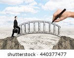 Success concept with hand drawing bridge over gap between two cliffs and businessman walking across it on landscape background