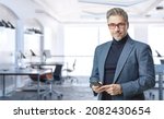 Small photo of Business portrait - confident businessman in office. Trustworthy older man in his 50s with gray hair wearing glasses and jacket. Copy space.