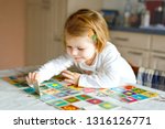Adorable cute toddler girl playing picture card game at home or nursery. Happy healthy child training memory, thinking. Development step and education of kid.