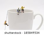 Miniature peoples climb up from coffee cup