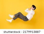 Young good looking asian man floating while listen with headphone isolated on yellow background