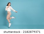 Young beautiful asian woman with smart casual cloth jumping and smiling with excitement looking at copy space isolated on blue background