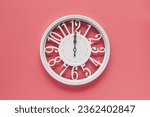 Small photo of Modern white clock with a circle on a pink wall background, twelve o'clock on the clock. Elegant clock in the modern style, combination of white and pink colors