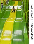 Small photo of Small girl (female age 04) slid on a giant slid in indoor playground. Real people. Copy space