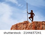 Small photo of MOUNT MAGNET, WA MAR 31 2022:Sculpture of Aboriginal Australian male standing on the Granites near Mount Magnet in Western Australia Outback.Aboriginal Australians settled across Australia 6000 years