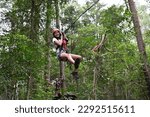 Small photo of Teenager girl (female age 12) sliding on a flying fox zip line during a treetop adventure climbing. Girls power, risk and challenge concept. Real people. Copy space