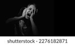 Small photo of Conceptual image: pain in children. Psychological portrait of nervous and overexcited young girl screamsfor help. Black and white image. Copy space for text.