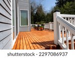 Freshly stained walk out home outdoor cedar wood deck with potted plants in bloom 