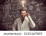 A smart eccentric scientist stands at the blackboard with scientific formulas and diagrams with a strange invention on his head and laughs madly. Science and new inventions.