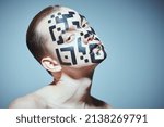 Small photo of The concept of depersonalization and control over society. Portrait of a young man with a QR-code painted on his face, looking unfriendly directly at the camera. Studio portrait on a gray background.