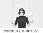 Small photo of A woman in black clothes stands in a white room surrounded by different masks. Hypocrisy. Mental disorders. Human roles. Black and white shot.