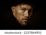 Small photo of Close up portrait of a pensive mature man with beard and moustache dressed in black coat and black hat looking calmly and thoughtfully. Black background. Psychological picture.