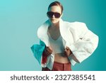 Small photo of Beautiful fashion model girl posing in designer clothes on blue studio background with place for text. Fashion haute couture collection. Wide free forms in clothes, oversized style.