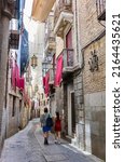 Small photo of Toledo, Spain - June 30, 2022. A couple walking through Alfileteros street, a typical street of Toledo downtown. Toledo, Castilla La Mancha, Spain.