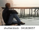 Man sitting on old wooden dock and looking at lake horizon. Thinking, contemplation  relaxing, concentration, loneliness concept