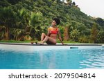 Small photo of A beautiful young African descent woman relaxing poolside drinking healthy fruit juice - African American girl sunbathing by the swimming pool - travel and vacation concept