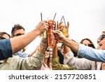 Group of young friends raises plastic glasses with spritz and fruit cocktails for a celebrate toast against a white background sky - concept of happy people having fun outdoors drinking and clinking