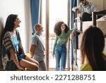 Small photo of A group of diverse young adults relax in a hostel dorm room, laughing and chatting together. One individual has a shaved head, piercings, and androgynous appearance - diversity and people lifestyle