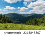Small photo of Jeseniky mountains with Kouty nad Desnou village bellow, meadow with flowers, hills and blue sky with clouds from hiking trail bellow Dlouhe strane hill in Czech republic