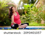 Pregnancy yoga. Exercise for pregnant woman. Active Asian female exercising at home or gym. New expectant mom keeping active and fit before childbirth. Sport for expecting mother. Online class.