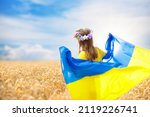 Pray for Ukraine. Child with Ukrainian flag in wheat field. Little girl waving national flag praying for peace. Happy kid celebrating Independence Day.